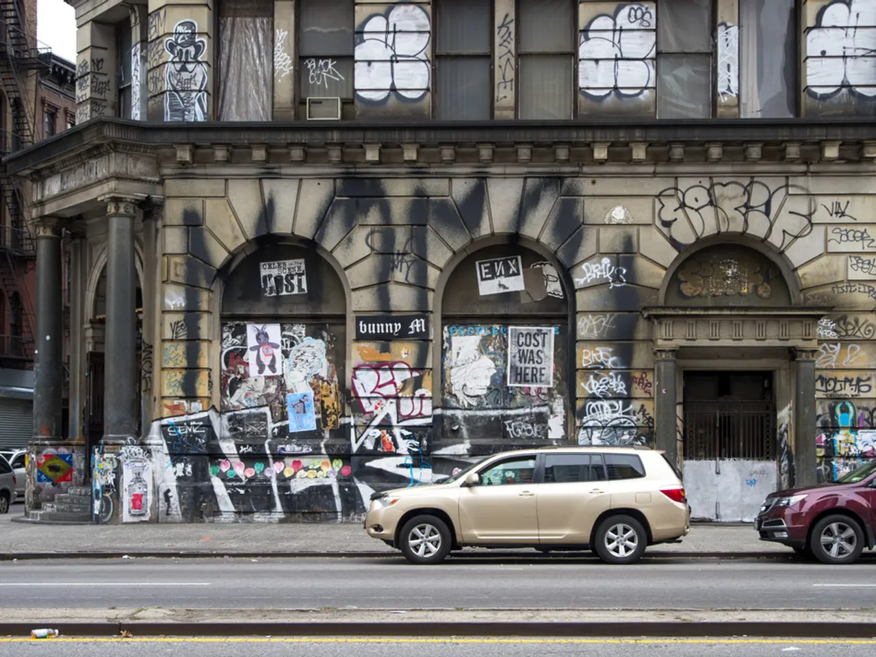 In this image we can see buildings with graffiti on them, grills, staircases, railings, sky and...