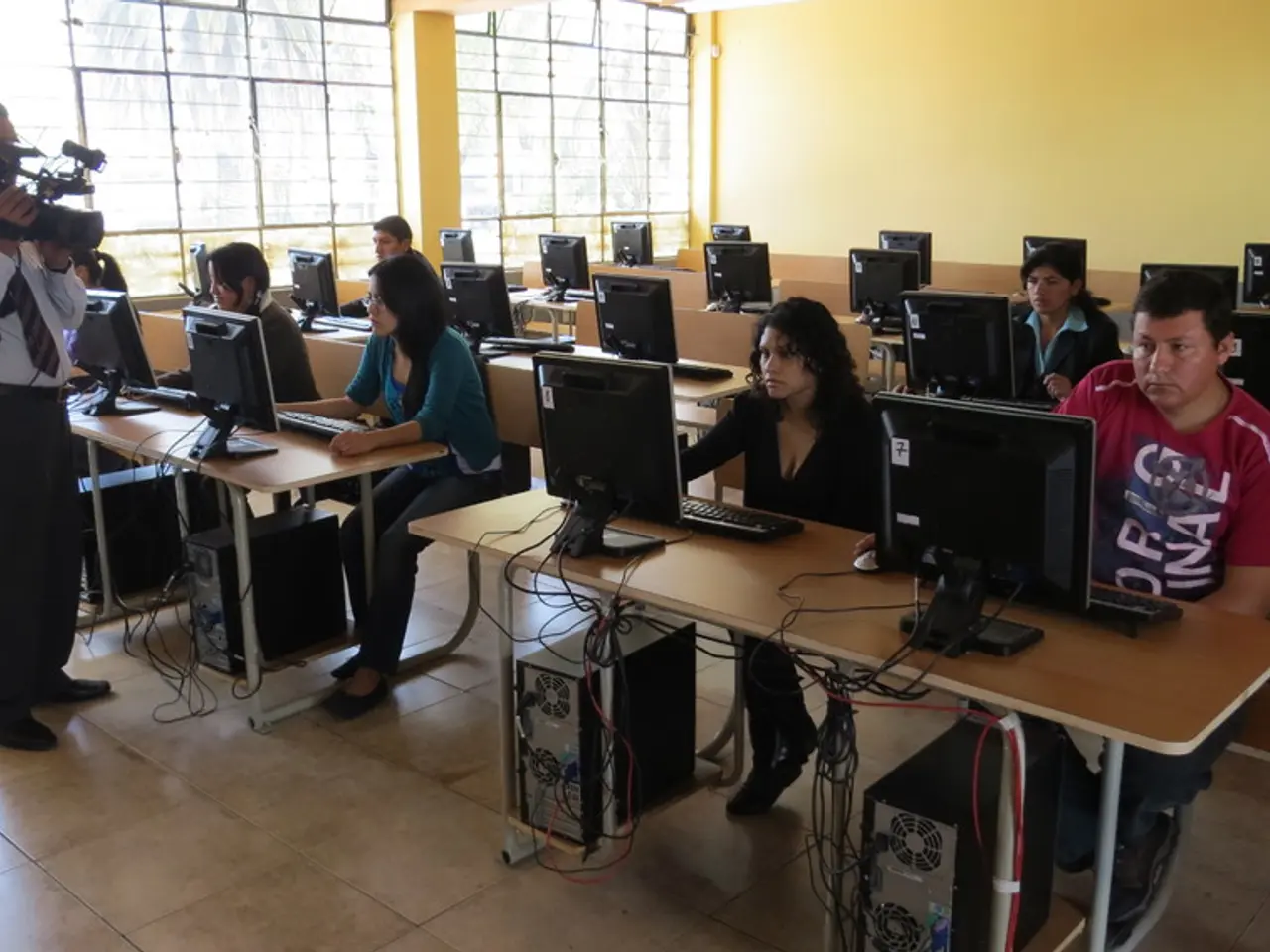 This is a classroom. There are few people sitting here, a group of people in front of monitors...