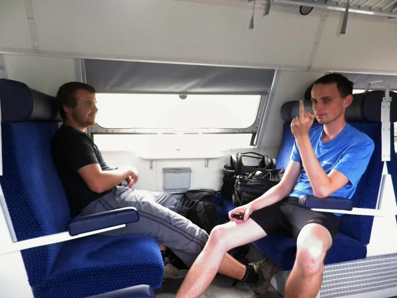 In this image in the center there are persons sitting and smiling and there are bags in the front....