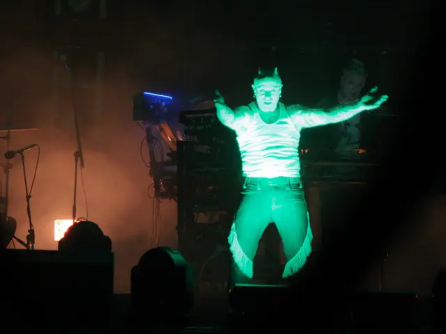 This image consists of a man. It looks like he is acting in a play. In the background, there are...