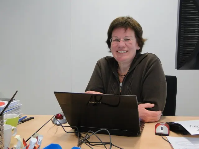 In this image I can see a person wearing black color dress is sitting on a black colored chair in...