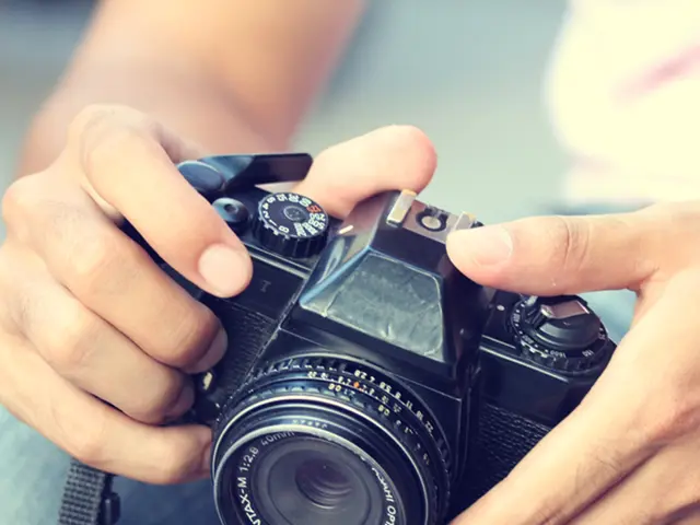 In this image we can see a person holding a camera.