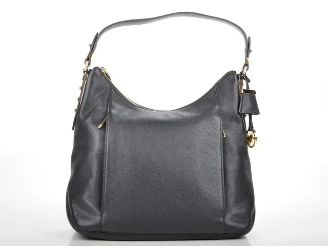 In this picture we can see a black color bag with belt and some chain to it.