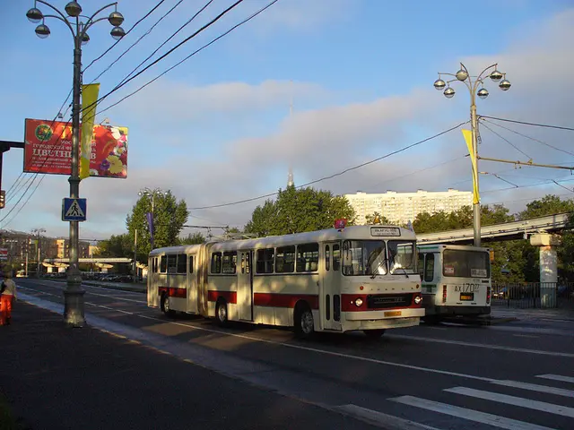 In the foreground of this picture, there are two buses moving on the road to which poles, trees,...