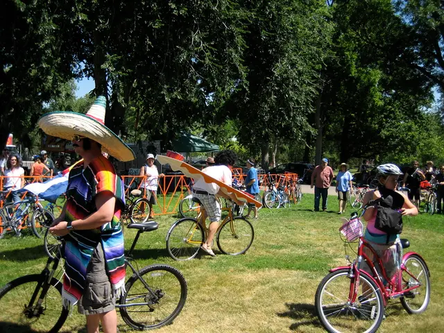 In this image there are so many people riding bicycles on the ground also there is a fence at the...